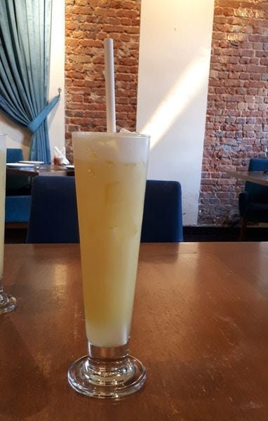 a tall glass of pineapple juice with a straw
