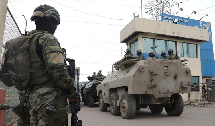 A soldier watches as armoured personnel carriers enter a jail in Ecuador.