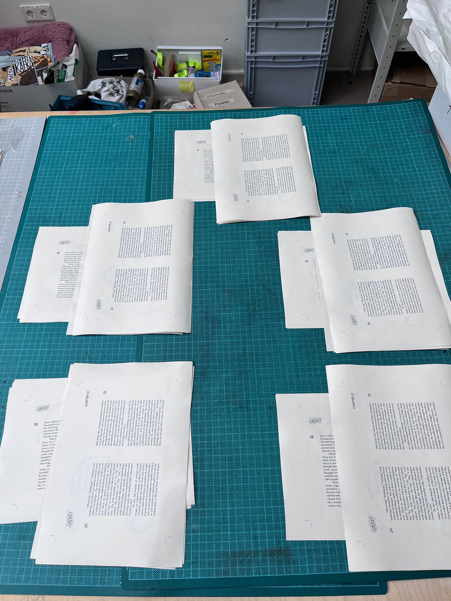 Five piles of pages from LAMB, arranged in their sections, are lying on a table ready to be folded. 