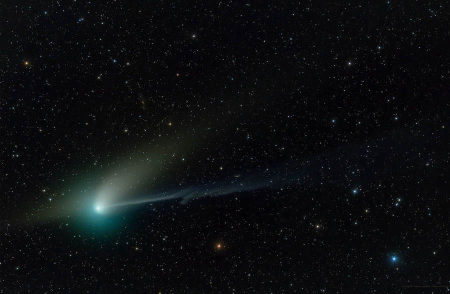 A comet against a backdrop of stars. The comet looks like a bright, greenish smudge with two different "tails."