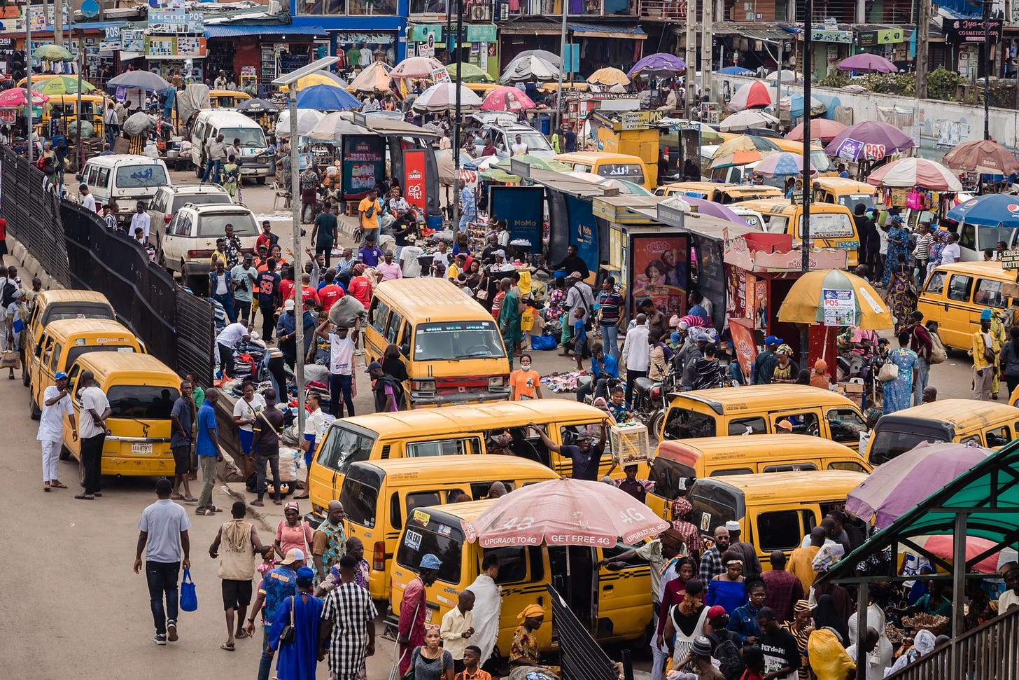 Market stall vendors and passengers at a taxi rank in Lagos, Nigeria.