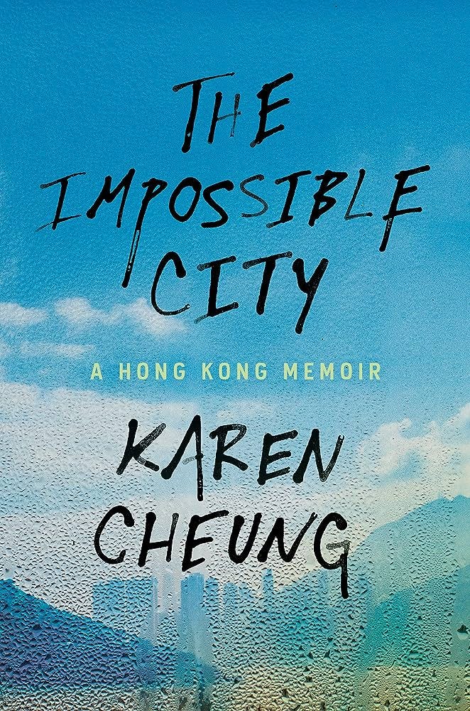 Capa do livro The Impossible City, de Karen Cheung. Na capa, é possível ver um céu azul ensolarado com algumas nuvens brancas e um panorama de Hong Kong, com prédios, montanhas e mar, tudo isso por trás de o que parece ser um vidro embaçado de umidade.