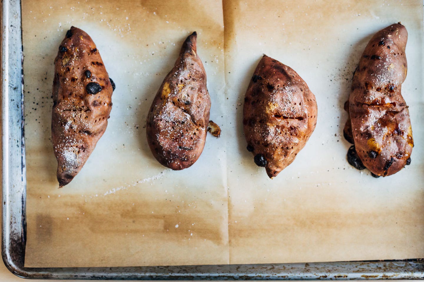 Roasted sweet potatoes on a parchment-lined baking sheet.