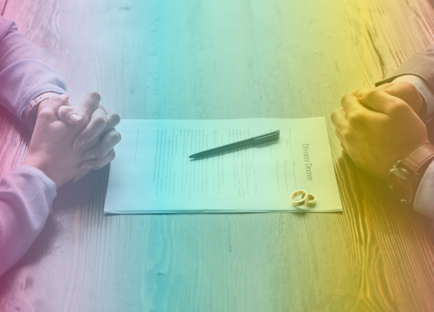 A rainbow-filtered image showing two sets of clasped hands on either side of a stack of papers labeled "Divorce Decree" with two gold wedding bands sitting on it