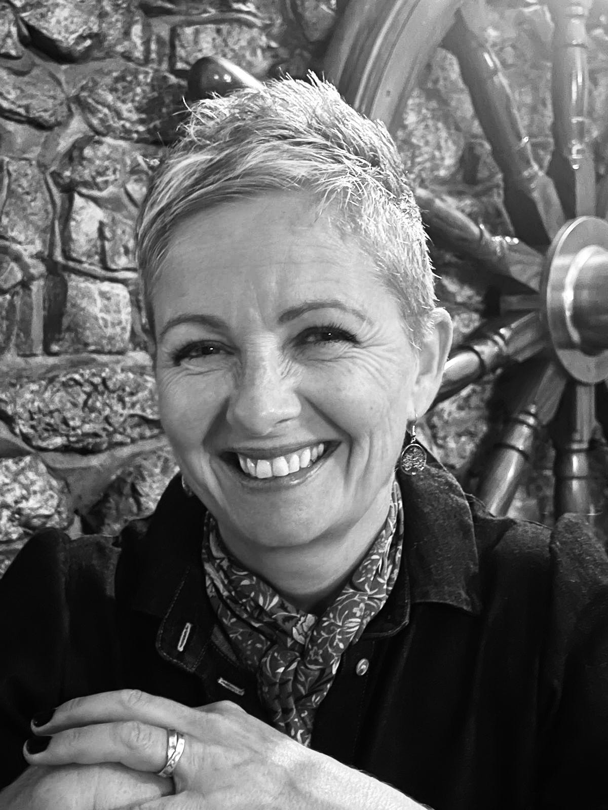 Black and white photo of short haired women in her mid fifties smiling at the camera