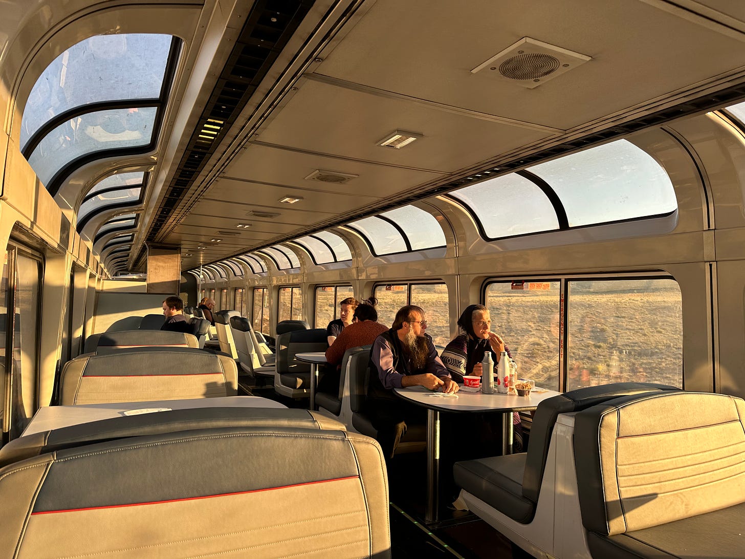 Morning light in the Amtrak sightseer lounge car with big windows and couples sitting