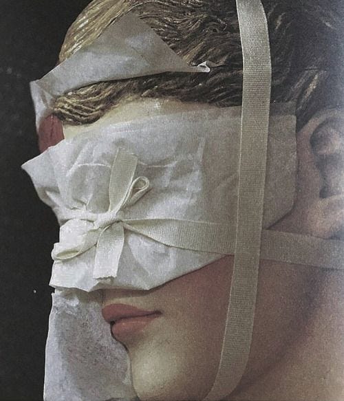 This may contain: a woman's head is wrapped in paper and tied up to a blindfold