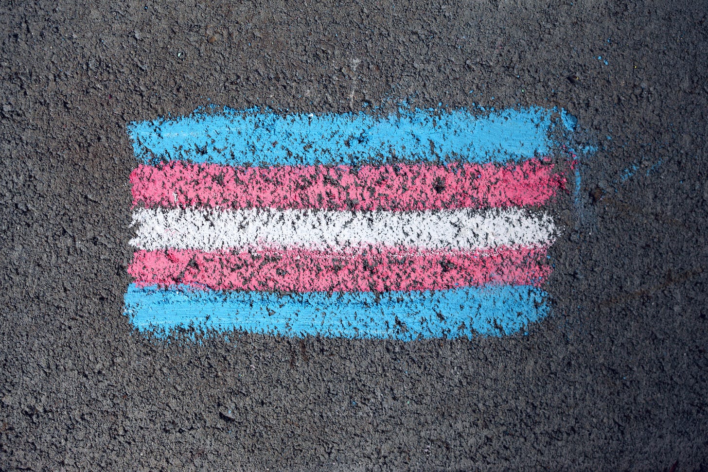 Trans flag on dark grey asphalt in bold sidewalk chalk