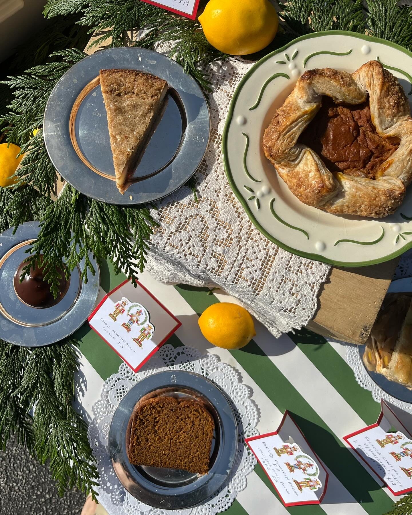 Table set with plates of various baked goods, garland, and lemons atop green and white striped paper.