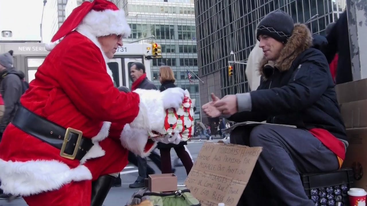 Santa "Mike" handing a gift to a grateful homeless person on a NYC street.