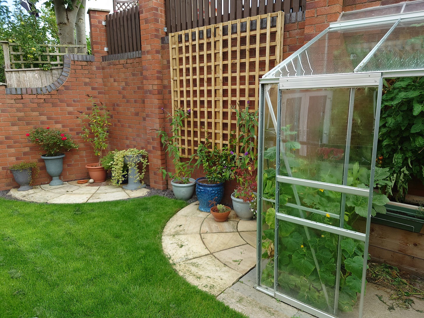 Photo of stone arcs, large trellis and greenhouse