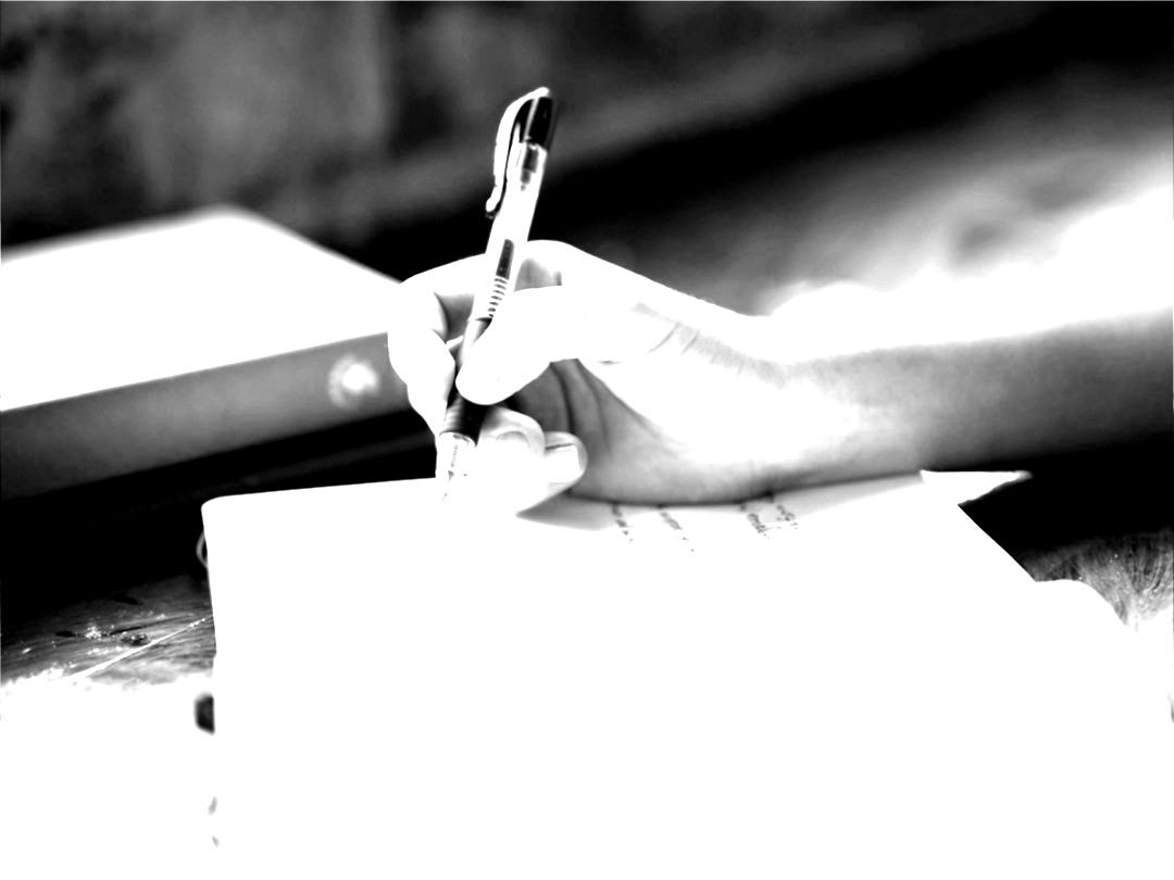 a person writing on a piece of paper with a pen a person writing on a piece of paper with a pen
