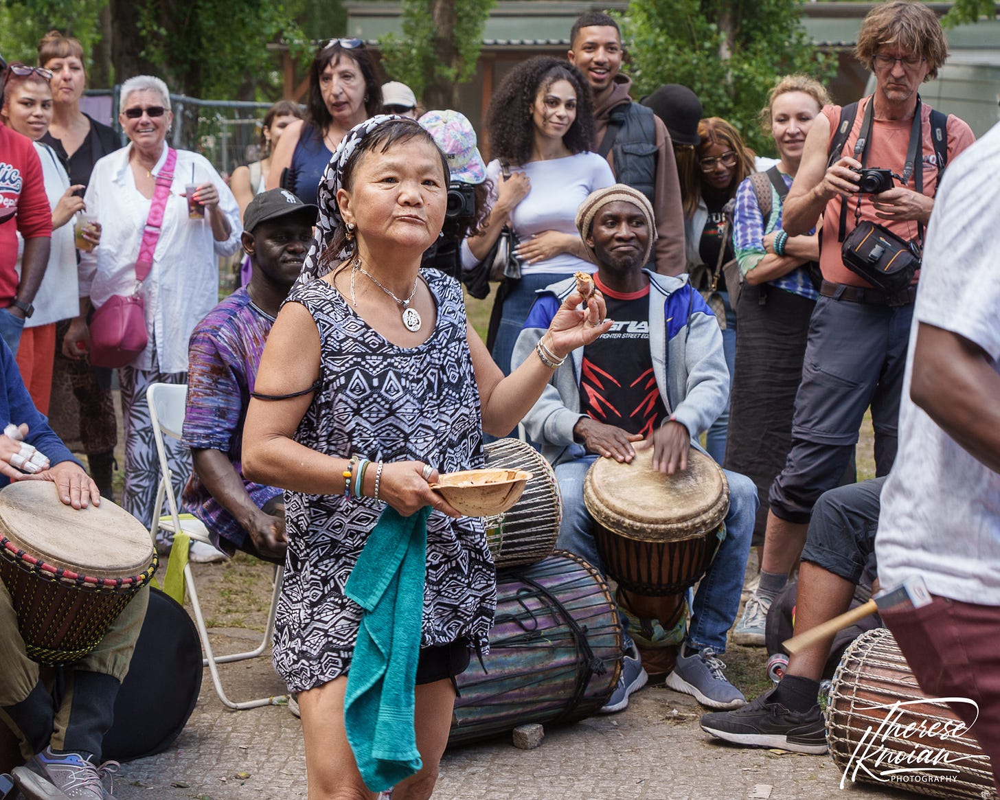 Photo of a woman dancing to Jamaican drummers holding a piece of chicken.