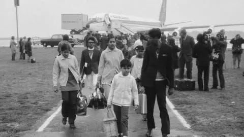 Getty Images Ugandan Asian refugees arriving at Stansted Airport in September 1972.