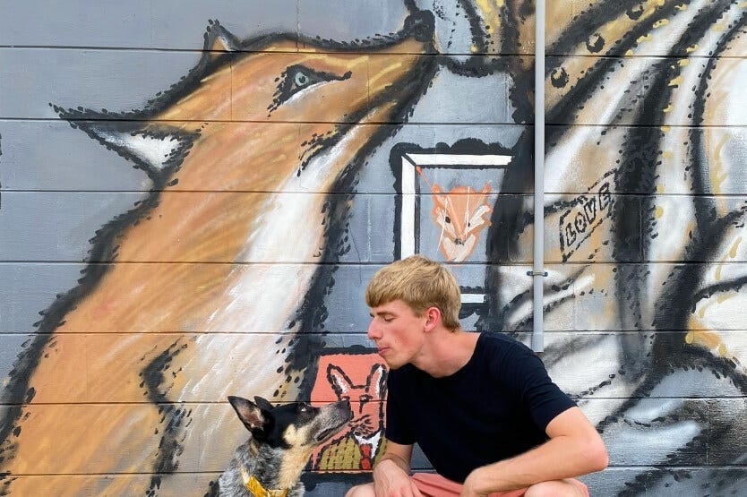 Scout the Australian cattle dog posing with her owner in front of a mural in the Eau Gallie Arts District in Florida