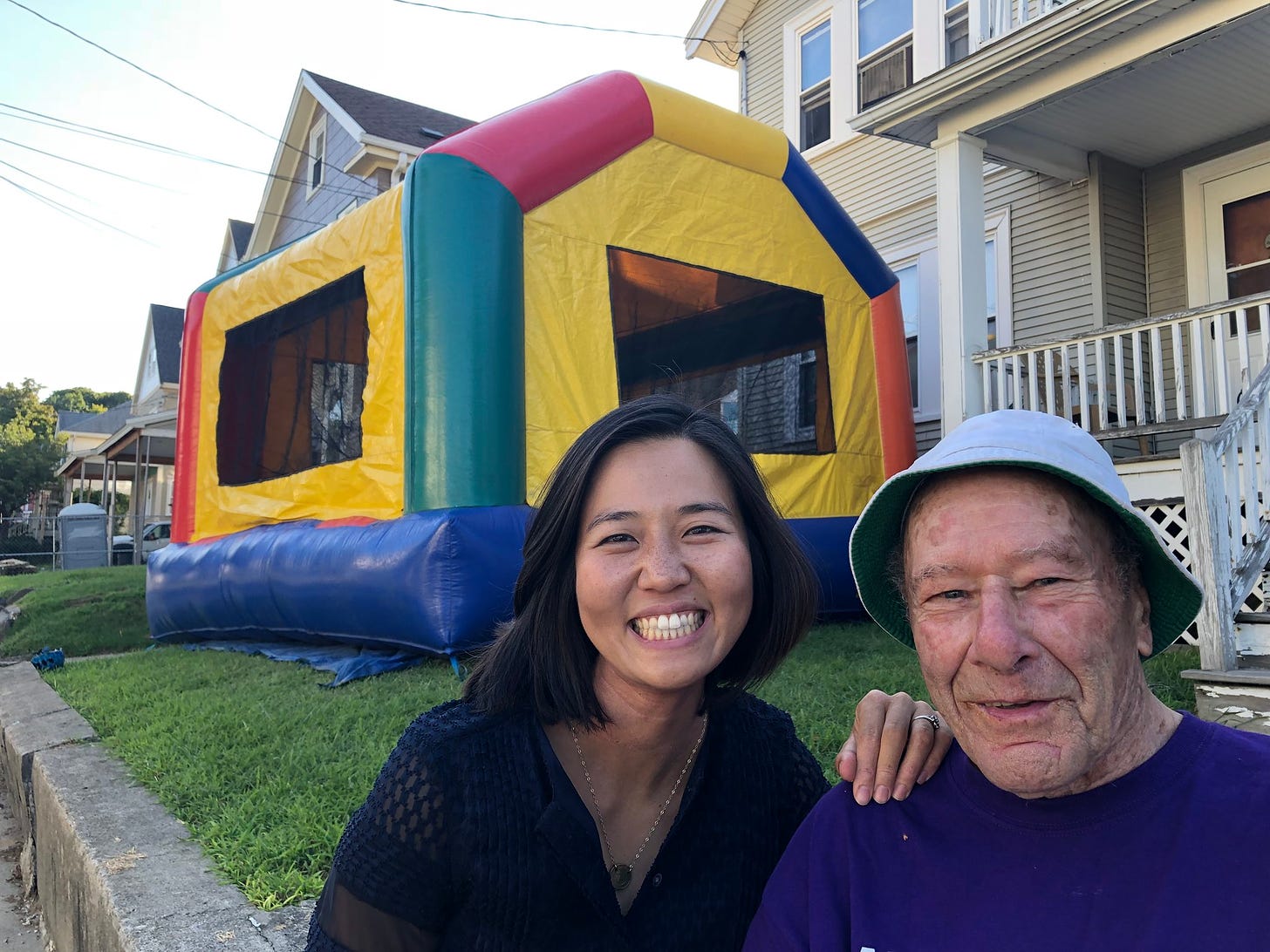 Michelle takes a picture with her neighbor Joe in front of the bouncy house set up for the block party