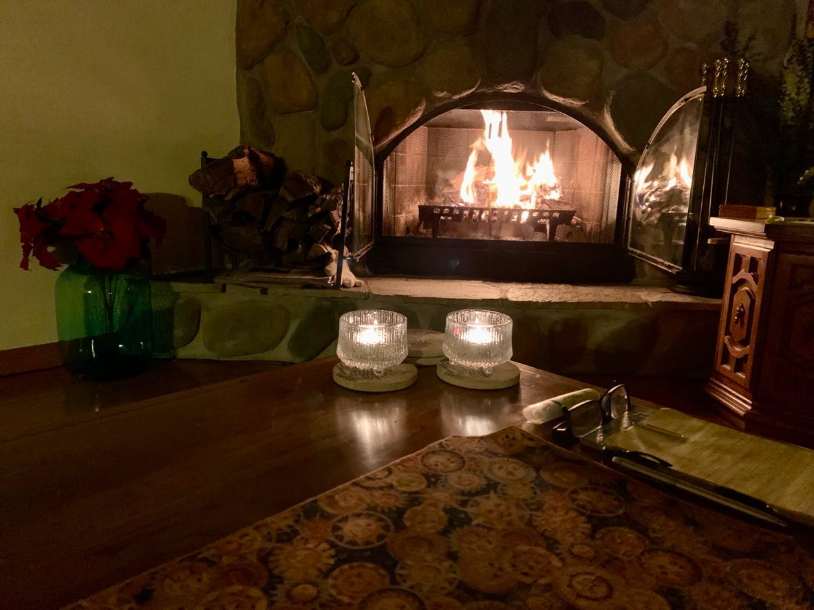 A table with candles on it and a fireplace in the background

Description automatically generated