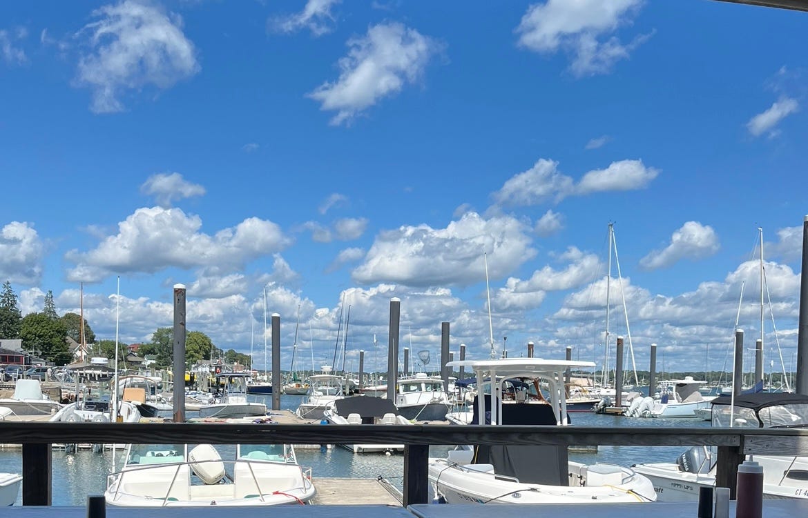 White boats moored in a harbor. The sky is blue with white clouds.