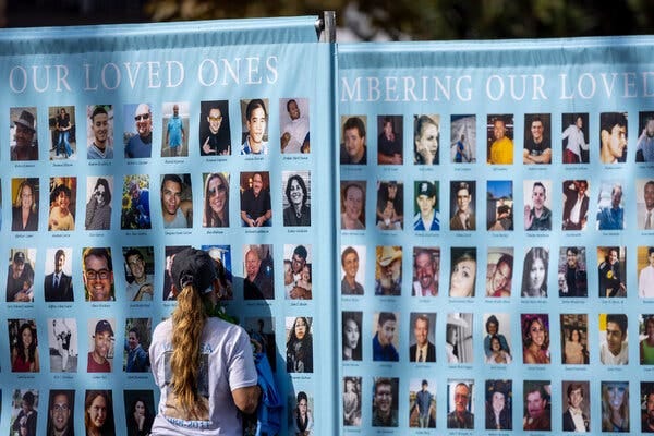A woman presses against a large sheet that displays photos of people who died by suicide. A heading at the top reads “Remembering Our Loved Ones.”