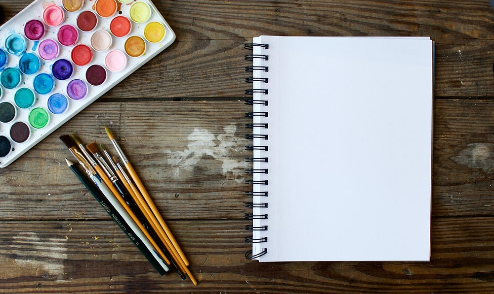 Photo of a blank notepad with paint brush next to it