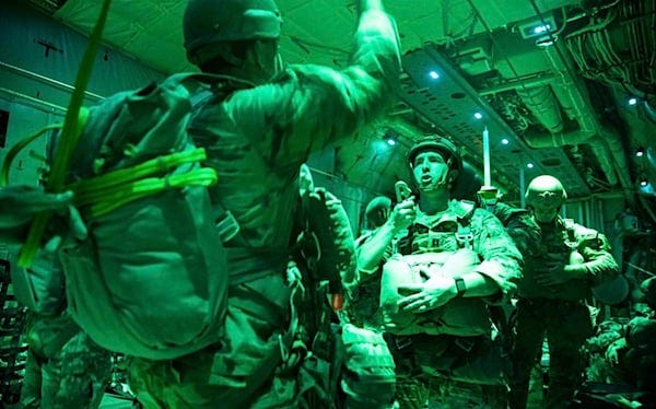 Paratroopers receive commands from a jumpmaster inside a C-130 Hercules over Son Tay Drop zone at Camp Rudder, Florida, Oct. 26, 2022. The jump was performed to develop and maintain proficiency in night airborne operations. (U.S. Army photo by Staff Sgt. Daniel Lee)