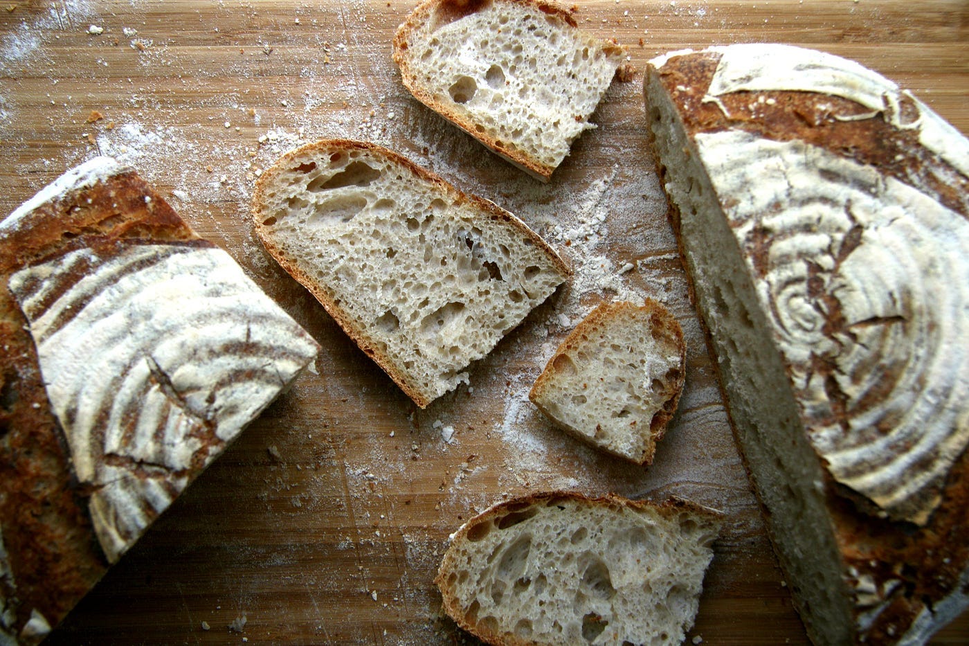 Sourdough bread cut into pieces on a wooden cutting board. Preparing to make bruschetta.