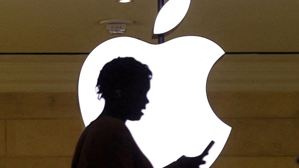photograph of someone checking their phone infront of an apple logo