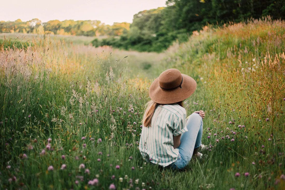 woman sat in a wild flower meadow woman sat in a wild flower meadow