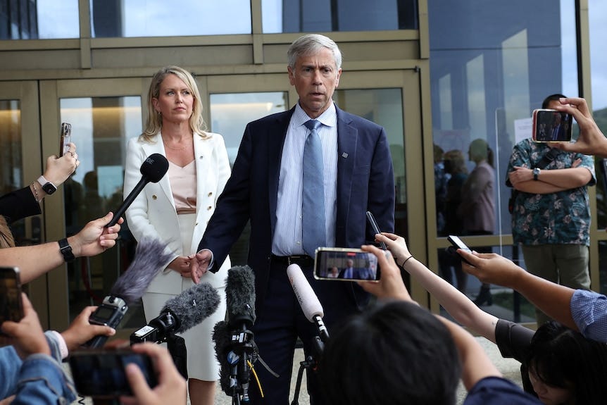 Un homme en costume marche devant le palais de justice