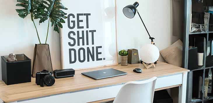 Photo of a desk with a sign in front reading "Get shit done".