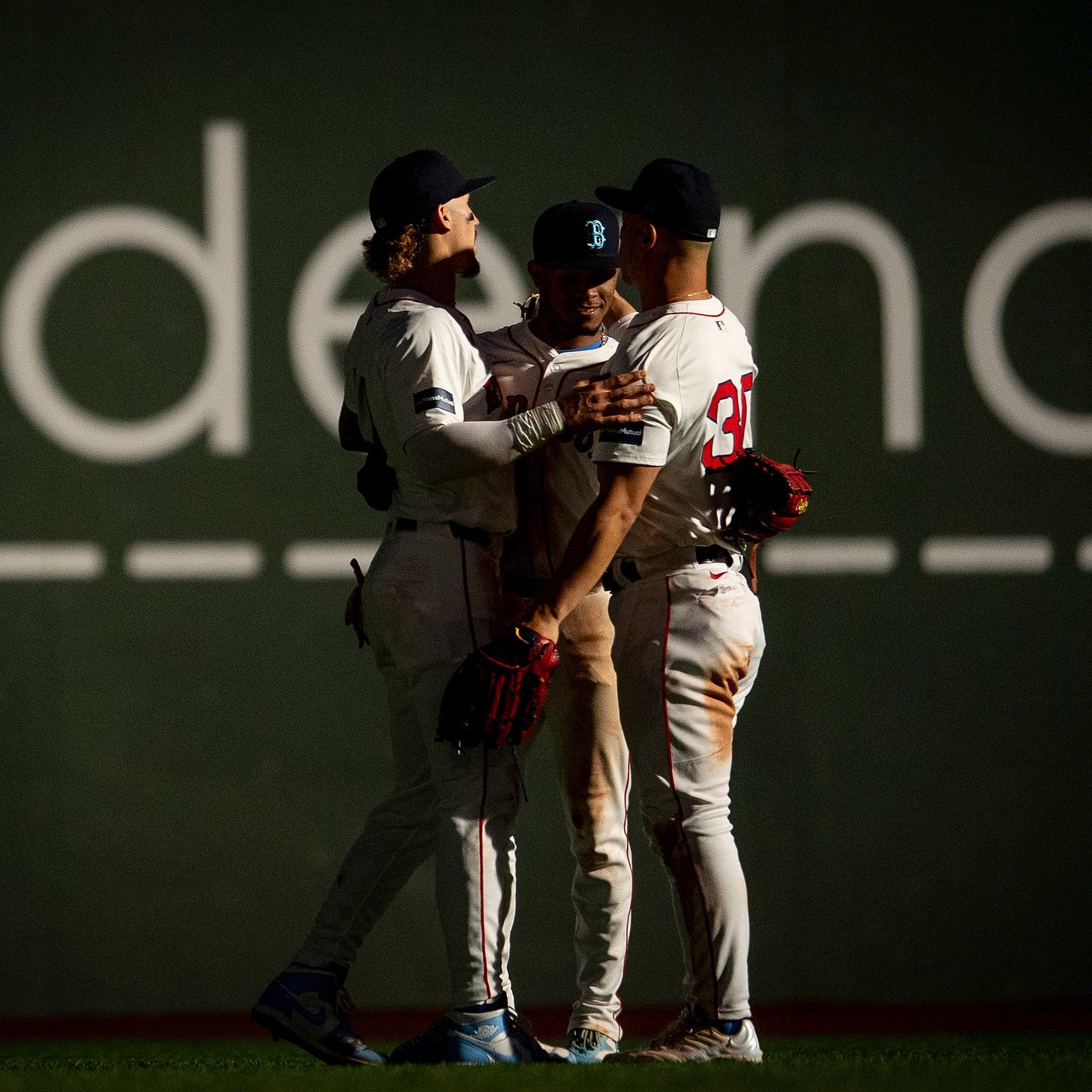 Ceddanne Rafaela, Rob Refsnyder, and Jarren Duran meet and embrace in center field at Fenway Park as the lights flicker following the win. 