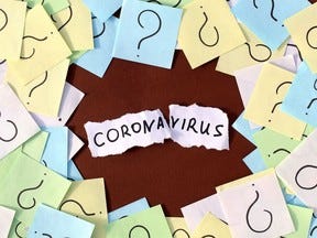 Stickers with question marks lie in a pile. The word coronavirus is written in the middle.