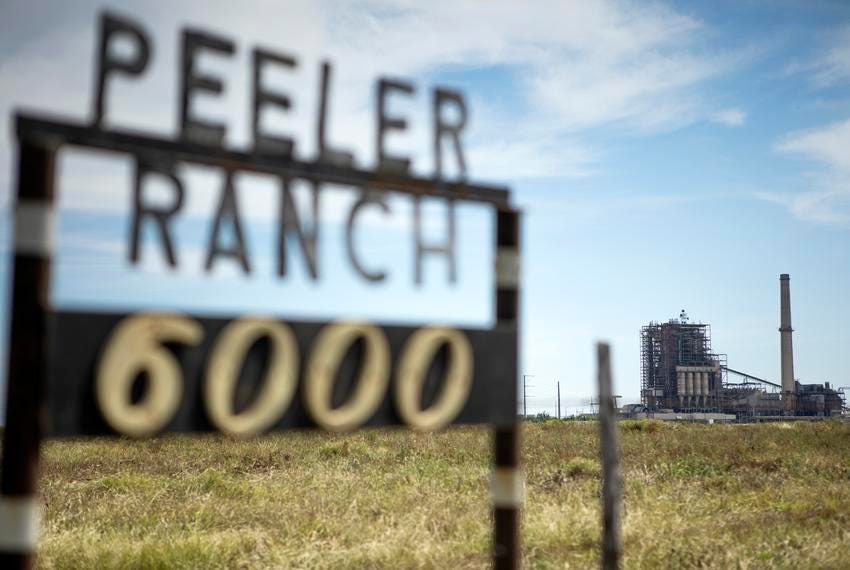 The San Miguel Electric Cooperative power plant can be seen in the background of a sign for the Peeler Ranch on April 26, 2019.