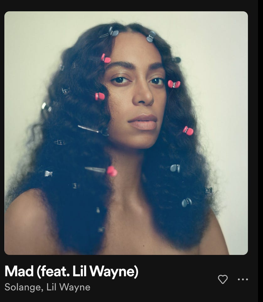 a screenshot of the song Mad by Solange Knowles (featuring Lil Wayne) off spotify. Solange is featured in the songs accompanying art, with clips in her wavy, long hair. She gazes directly into the camera. 