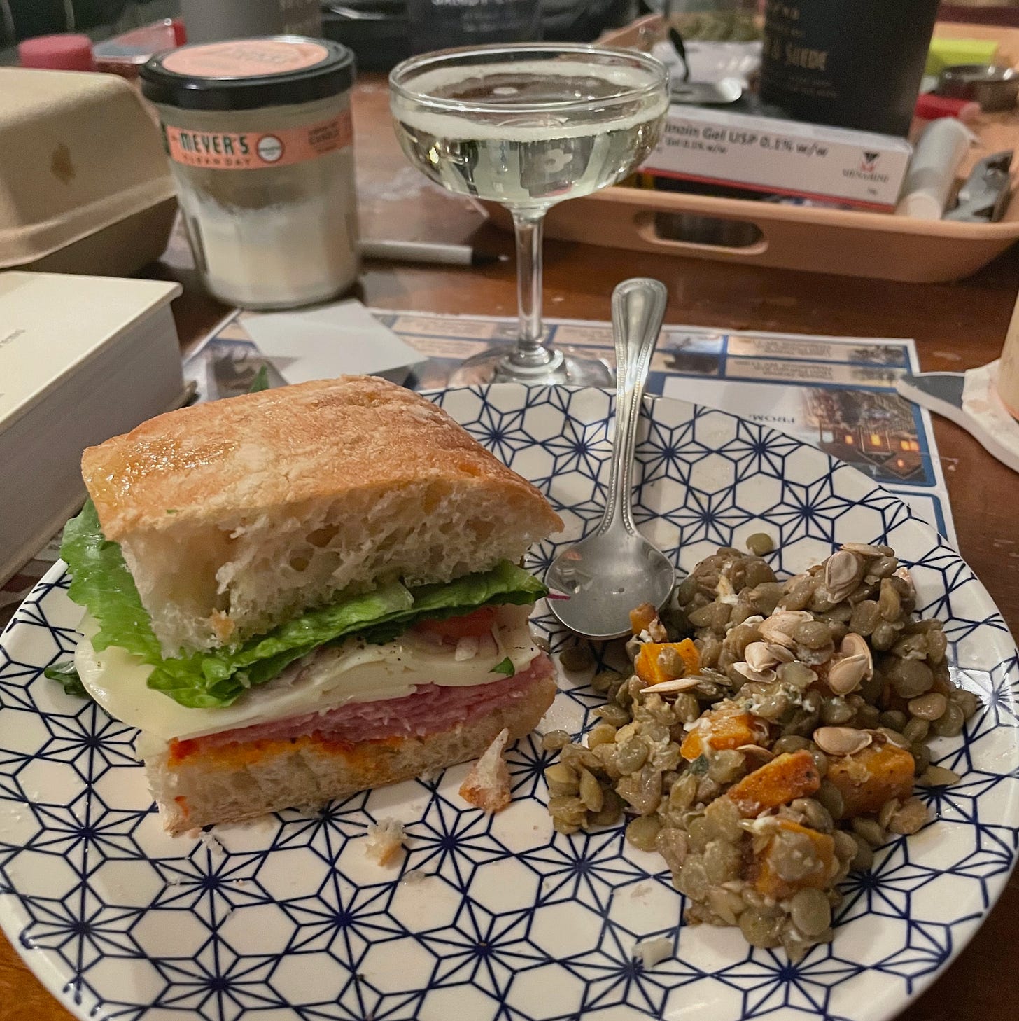 plate with sandwich and squash lentil salad with champagne glass behind it