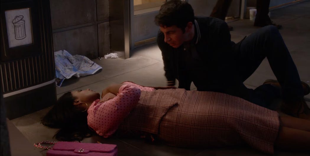 A screenshot from the "Danny and Mindy' episode of The Mindy Project; Mindy lies on the floor by a trashcan, exhausted, while Danny crouches down to check on her