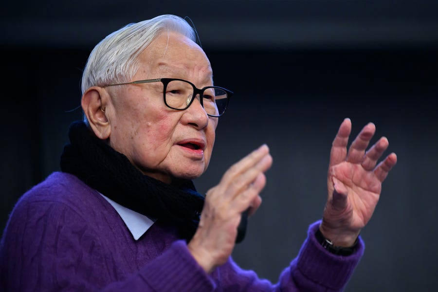 Closeup of Morris Chang as he gestures with his hands, while wearing a scarf and purple sweater. Closeup of Morris Chang as he gestures with his hands, while wearing a scarf and purple sweater.