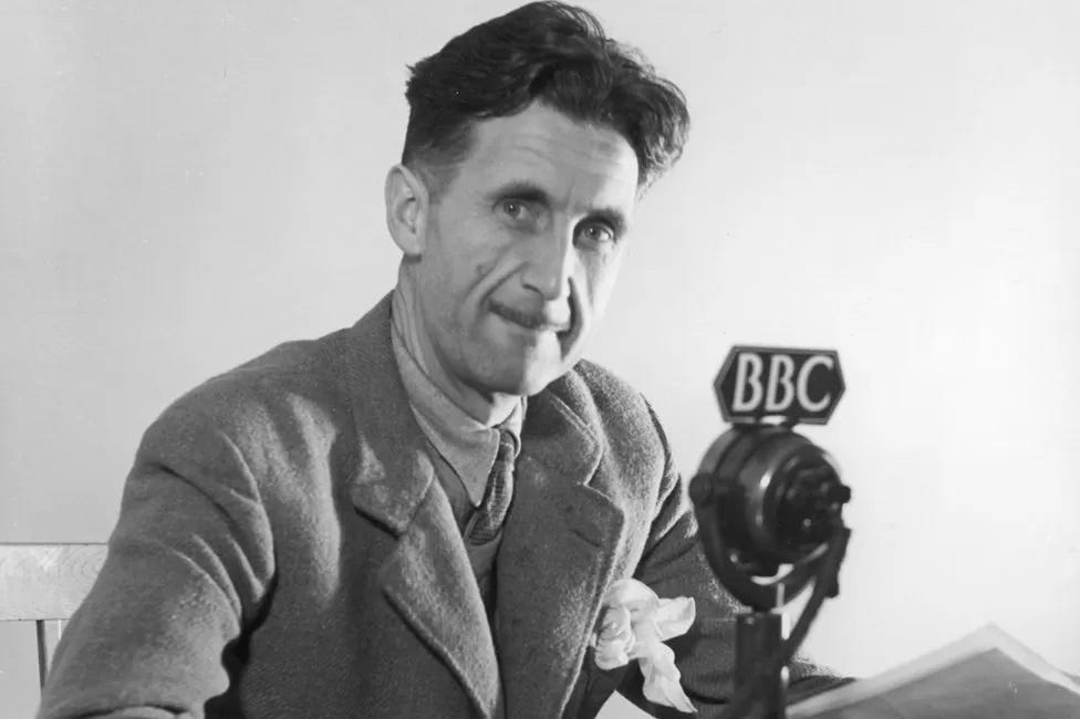 Black & white photo of George Orwell at a microphone with a 'BBC' logo sometime in the 1940s