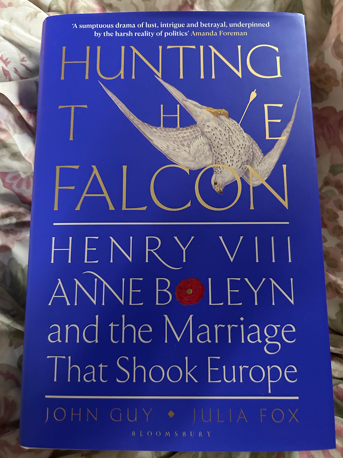A copy of Hunting the Falcon, a blue hardback, placed on a floral duvet
