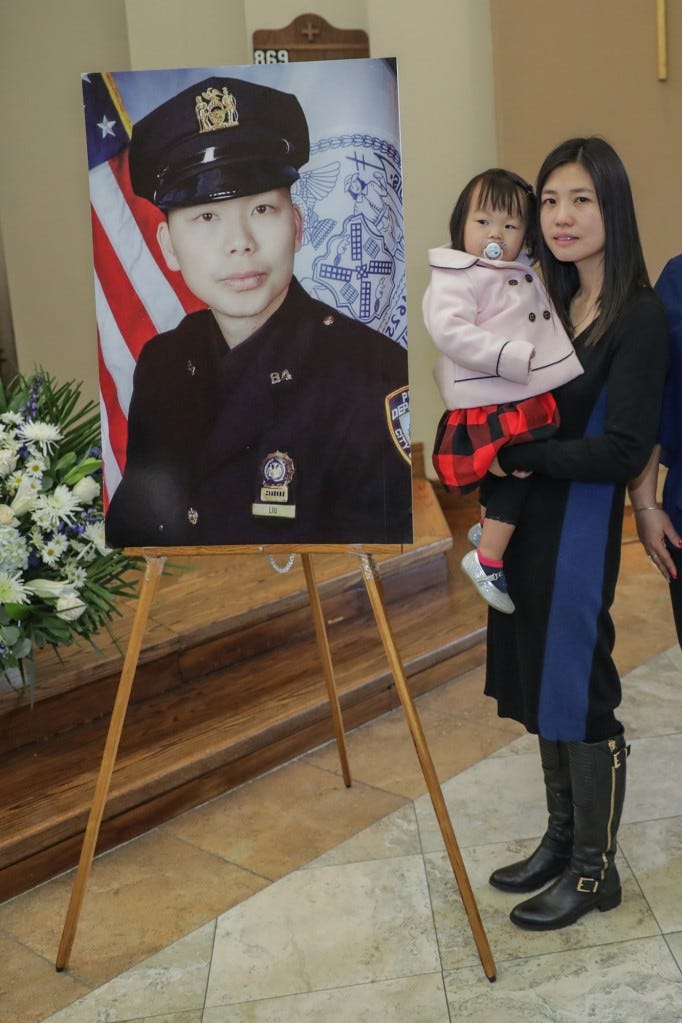 Pei Xia Chen holds her daughter Angelina, standing with a picture of her husband, slain NYPD officer Wenjian Liu.