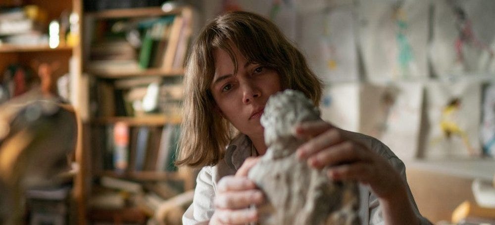 Movie still from Showing Up. A woman carefully sculpts a human sculpture in an art studio