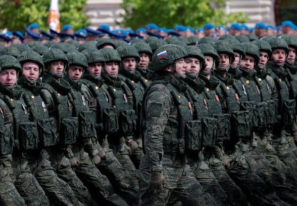 A large group of soldiers marching in columns at an outdoor event.