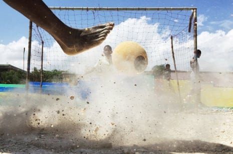 Foot kicking foam buoy towards a football goal in a cloud of dust