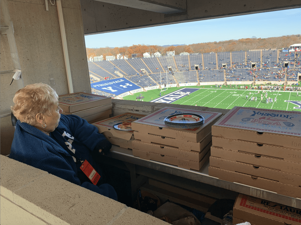 woman watching a football game with pizza boxes next to her