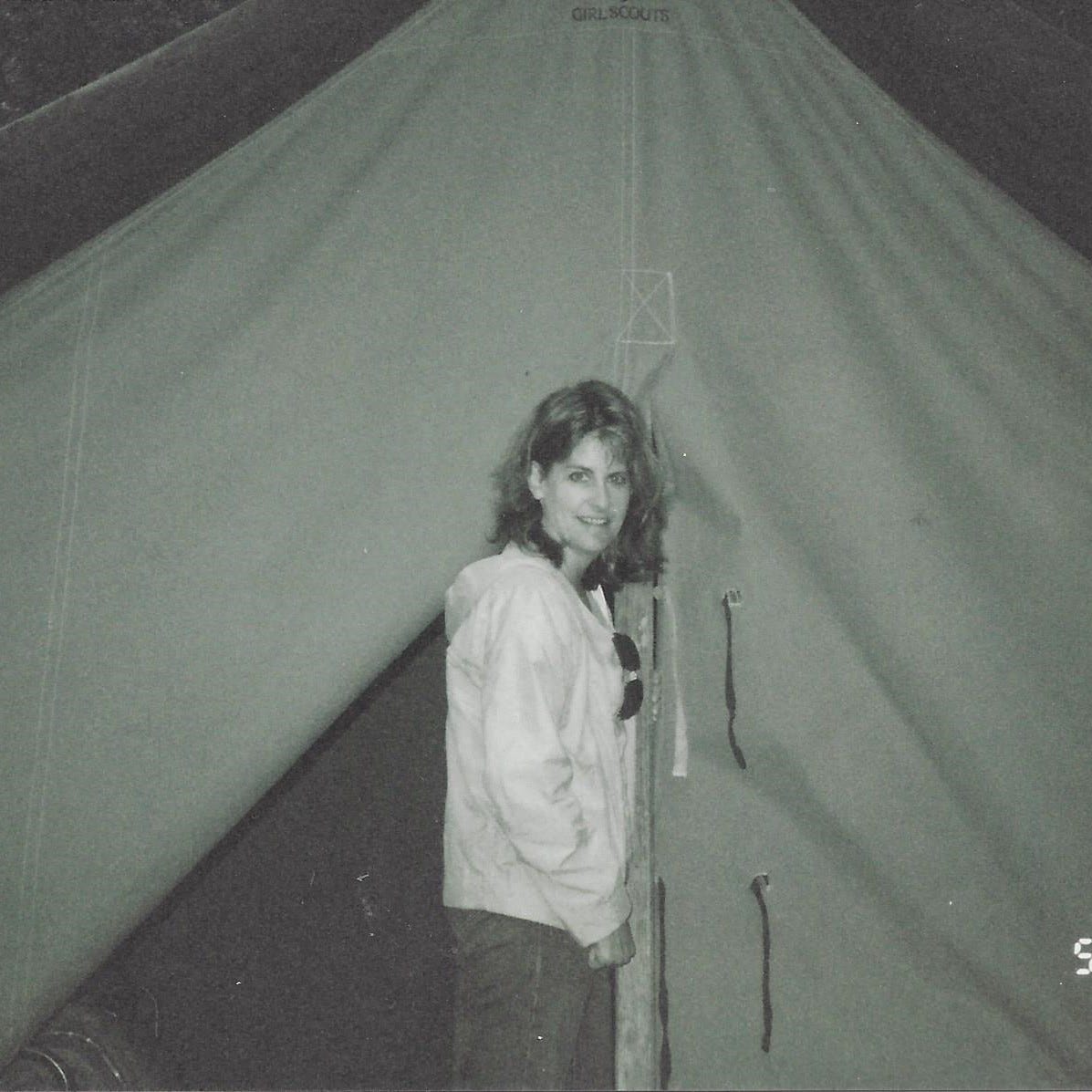 40-something woman cautiously peels back the flap of her tent