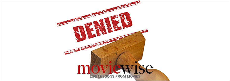A wooden stamp leaves a red mark with the word “denied” in large capital letters.