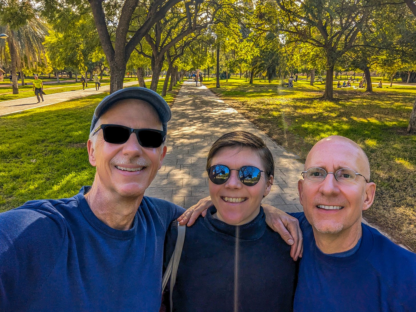 Michael, Marianne, and Brent walking under the green trees. 
