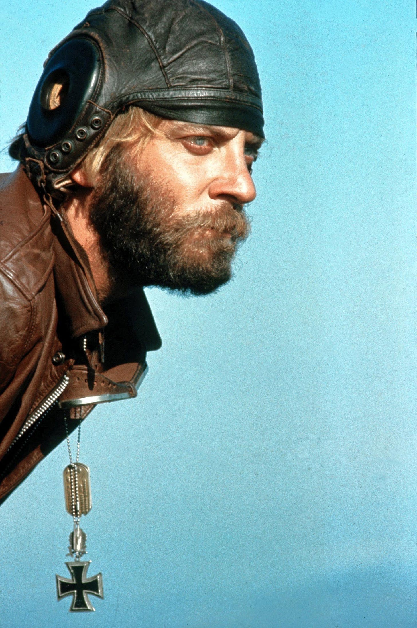 Profile portrait of actor Donald Sutherland wearing a leather military helment and a leather jacket and looking seriously into the distance in the film Kelly's Heroes