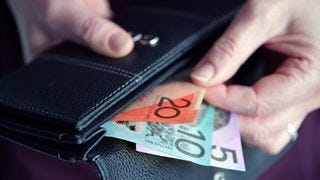 A hand pulling Australian cash out of a wallet