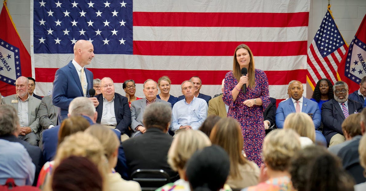 Photo of Sarah Huckabees Sanders in front of larg American flag at a speaking event